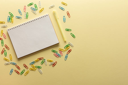 Open spiral notepad on yellow background , notebook and pen lie on textural paper, flat lay concept...