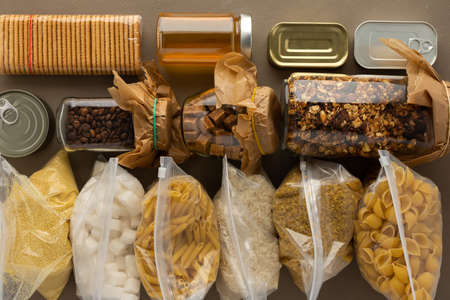 Home food supplies, necessary food for the period of quarantine and isolation, the concept of stay at home, canned food , various pasta and flour, sugar and cookies, top viewの写真素材