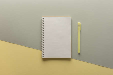 Open spiral notepad on gray and yellow background , notebook and pen lie on textural paper, flat lay concept in trendy colors of the year yellow and grayの写真素材