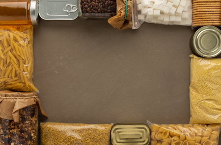 Home food supplies, necessary food for the period of quarantine and isolation, the concept of stay at home, canned food and honey, granola and cookies, top view, copy spaseの写真素材