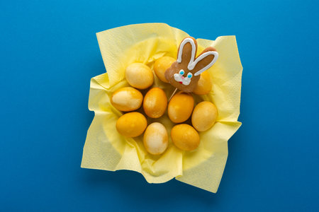 Easter yellow painted eggs and biscuits bunny in plate on bright blue background, easter festive conceptの写真素材