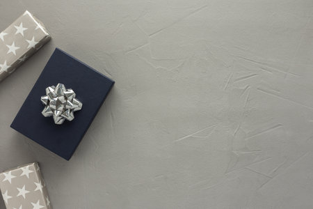 Blue gift box and a bow and gray boxes with stars on a gray concrete background, birthday or valentine concept, top view, copy spaceの写真素材