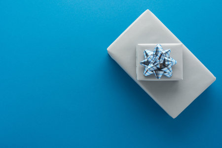 Gray gift boxes with a bow on a blue background, birthday or valentine concept, top view, copy space