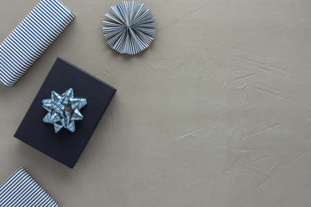 Blue striped gift boxes and paper christmas tree decorations and blue gift box on gray concrete background, concept for birthday or christmasの写真素材