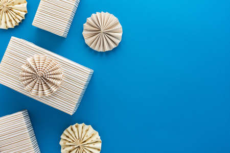 Goldern striped gift boxes and paper christmas tree decorations on blue background, concept for birthday or christmasの写真素材