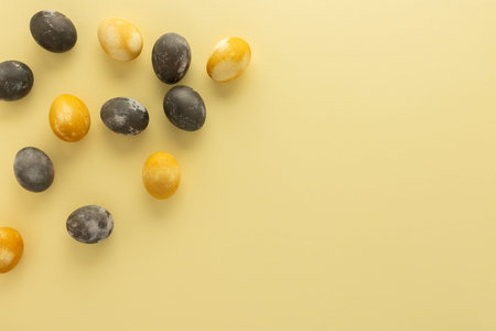 Golden and silver easter eggs scattered on yellow background, festive easter concept