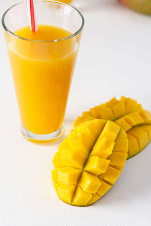 Mango juice in a glass with a straw on a white background, chopped mango fruit, delicious healthy sweet natural drinkの写真素材