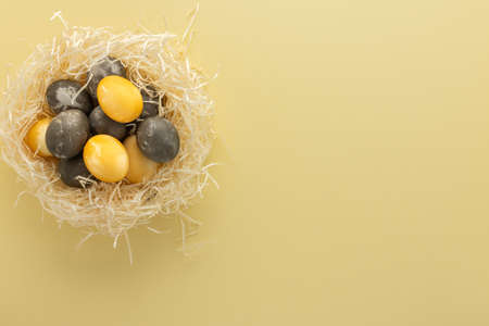 Golden and silver easter eggs in straw nest, easter nest isolated on yellow backgroundの写真素材