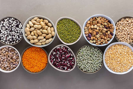 Different types of legumes in bowls, green and yellow peas, chickpeas and peanuts, colored beans and lentils, mung beans and beans, top viewの写真素材