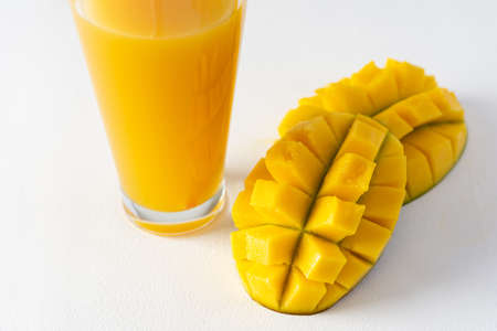 Mango juice in a glass with a straw on a white background, chopped mango fruit, delicious healthy sweet natural drinkの写真素材