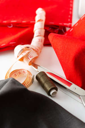 Modern sewing machine with red and gray fabric, measuring tape and thread and scissors, cutting and sewing at home, domestic leisure and hobbyの写真素材