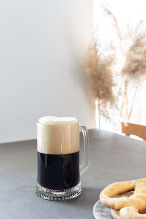 Dark craft beer in large beer mug and delicious homemade pretzels on gray backgroundの写真素材