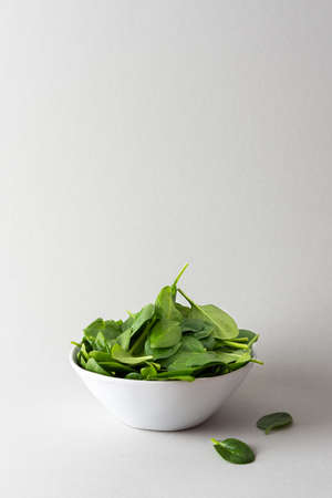 Healthy vegetable greens in a bowl on a gray background, green spinach leaves close upの写真素材