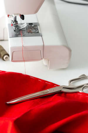Modern sewing machine with red and gray fabric, thread and scissors, cutting and sewing at home, home leisure and hobbyの写真素材