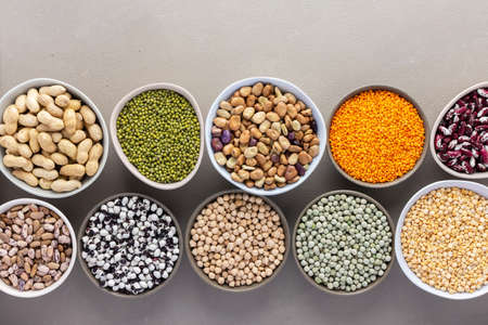 Different types of legumes in bowls, green and yellow peas, chickpeas and peanuts, colored beans and lentils, mung beans and beans, top viewの写真素材