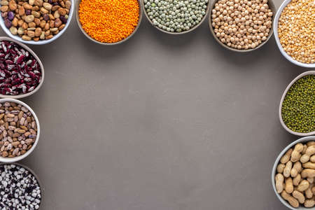 Different types of legumes in bowls, green and yellow peas, chickpeas and peanuts, colored beans and lentils, mung beans and beans, top viewの写真素材