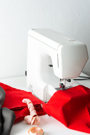 Modern sewing machine with red and gray fabric, measuring tape, cutting and sewing at home, home leisure and hobbyの写真素材