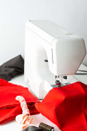 Modern sewing machine with red and gray fabric, measuring tape and thread, cutting and sewing at home, home leisure and hobbyの写真素材