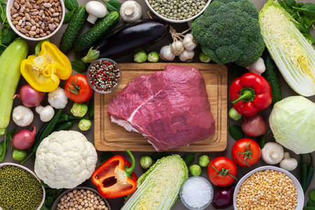 Fresh farm organic vegetables, healthy food concept, vegetables and mushrooms, superfoods and beans around the board with a large fresh piece of beef fillet, top viewの写真素材