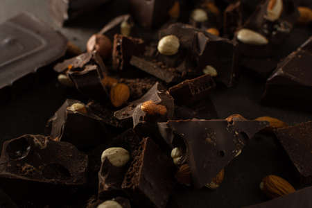 Dark chocolate with almonds and hazelnuts on brown backgroundの写真素材