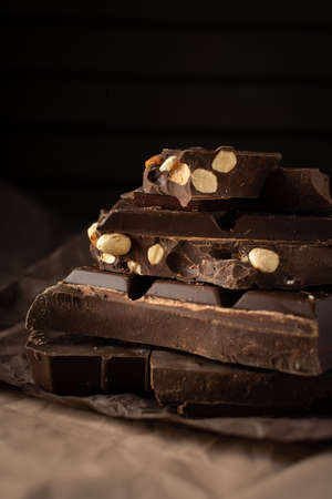 Dark chocolate with almonds and hazelnuts in a stack on brown backgroundの写真素材