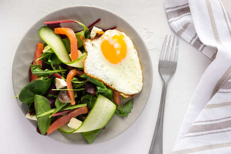 Fresh organic mesclun mix salad with cucumber, mozzarella and salmon, scrambled eggs, delicious hearty breakfastの写真素材