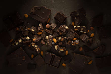 Dark chocolate with almonds and hazelnuts on a brown background, top viewの写真素材