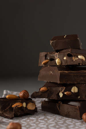 Dark chocolate with almonds and hazelnuts in a stack on brown backgroundの写真素材