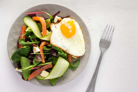 Fresh organic mesclun mix salad with cucumber, mozzarella and salmon, scrambled eggs, delicious hearty breakfastの写真素材