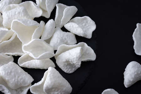 White crispy potato chips scattered on black backgroundの写真素材
