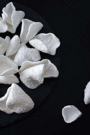 White crispy potato chips scattered on black backgroundの写真素材