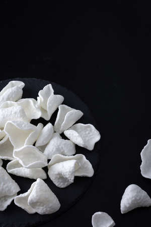 White crispy potato chips scattered on black backgroundの写真素材
