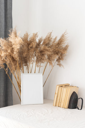 Home decor mock-up, blank picture frame near white painted concrete wall , dry Cane Reeds and old booksの写真素材