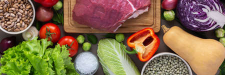 Fresh farm organic vegetables banner, healthy food concept, vegetables and mushrooms, superfoods and beans around the board with a large fresh piece of beef fillet, top viewの写真素材