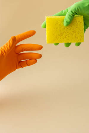 Hand in multi-colored rubber gloves hold a dishwashing sponge, cleaning conceptの写真素材