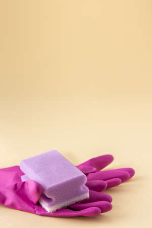 Purple dishwashing sponge and pink rubber gloves on neutral beige background, cleaning conceptの写真素材