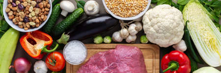 Fresh farm organic vegetables banner, healthy food concept, vegetables and mushrooms, superfoods and beans around the board with a large fresh piece of beef fillet, top viewの写真素材
