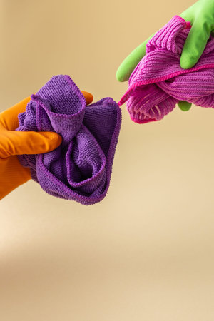 Hand in multi-colored rubber gloves holding a microfiber cloth for washing, cleaning concept