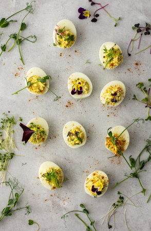 Eggs stuffed with sauce and fried onions with various microgreens, top view, delicious healthy...