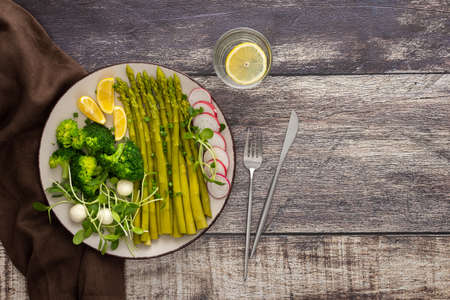 Delicious healthy breakfast, broccoli with asparagus, microgreens with mozzarella and radishes and lemon slicesの写真素材
