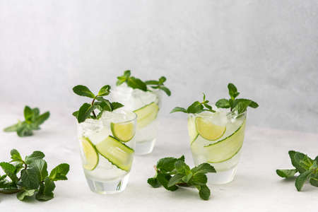 Cold refreshing drinks with lime and cucumber, summer iced beverage and fresh green mint, glasses with lemon waterの写真素材