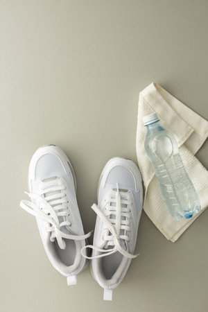 White sports sneakers with water bottle and towel on a gray background, doing sports and training in the hall, healthy lifestyle, top view, copy spaceの写真素材