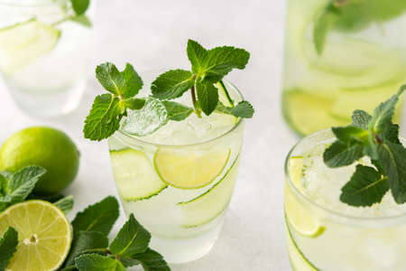 Cold refreshing drinks with lime and cucumber, summer iced beverage and fresh green mint, glass with lemon water close upの写真素材