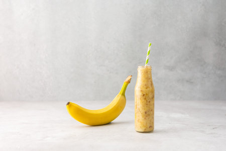 Whole ripe delicious banana fruit and banana smoothie in a jar with a straw, copy spaceの写真素材
