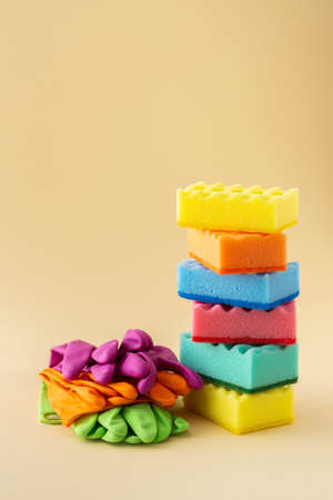 Stack of multicolored dishwashing sponges and rubber gloves on neutral beige background, kitchen household and cleaning conceptの写真素材