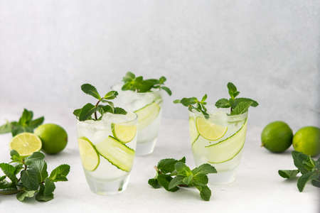 Cold refreshing drinks with lime and cucumber, summer iced beverage and fresh green mint, glasses with lemon waterの写真素材