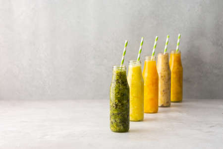 Fruit smoothies in jars with straws, pineapple and kiwi, banana and mango and orange smoothiesの写真素材