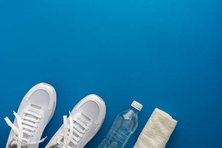 White sports sneakers with water bottle and towel on a blue background, doing sports and training in the hall, healthy lifestyle, top view, copy spaceの写真素材