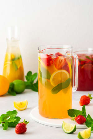 Jugs of fresh refreshing fruit drinks with fruit wedges, summer cold juices with iceの写真素材