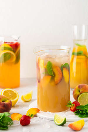 Jugs of fresh refreshing fruit drinks with fruit wedges, summer cold juices with iceの写真素材